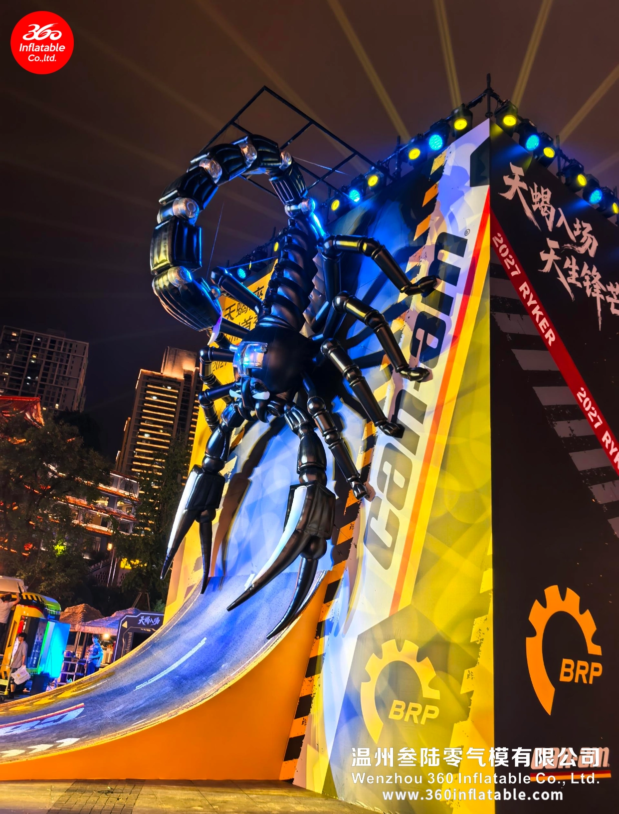 Side view of the Scorpio inflatable showing its raised mechanical tail and climbing posture against the city nightscape.