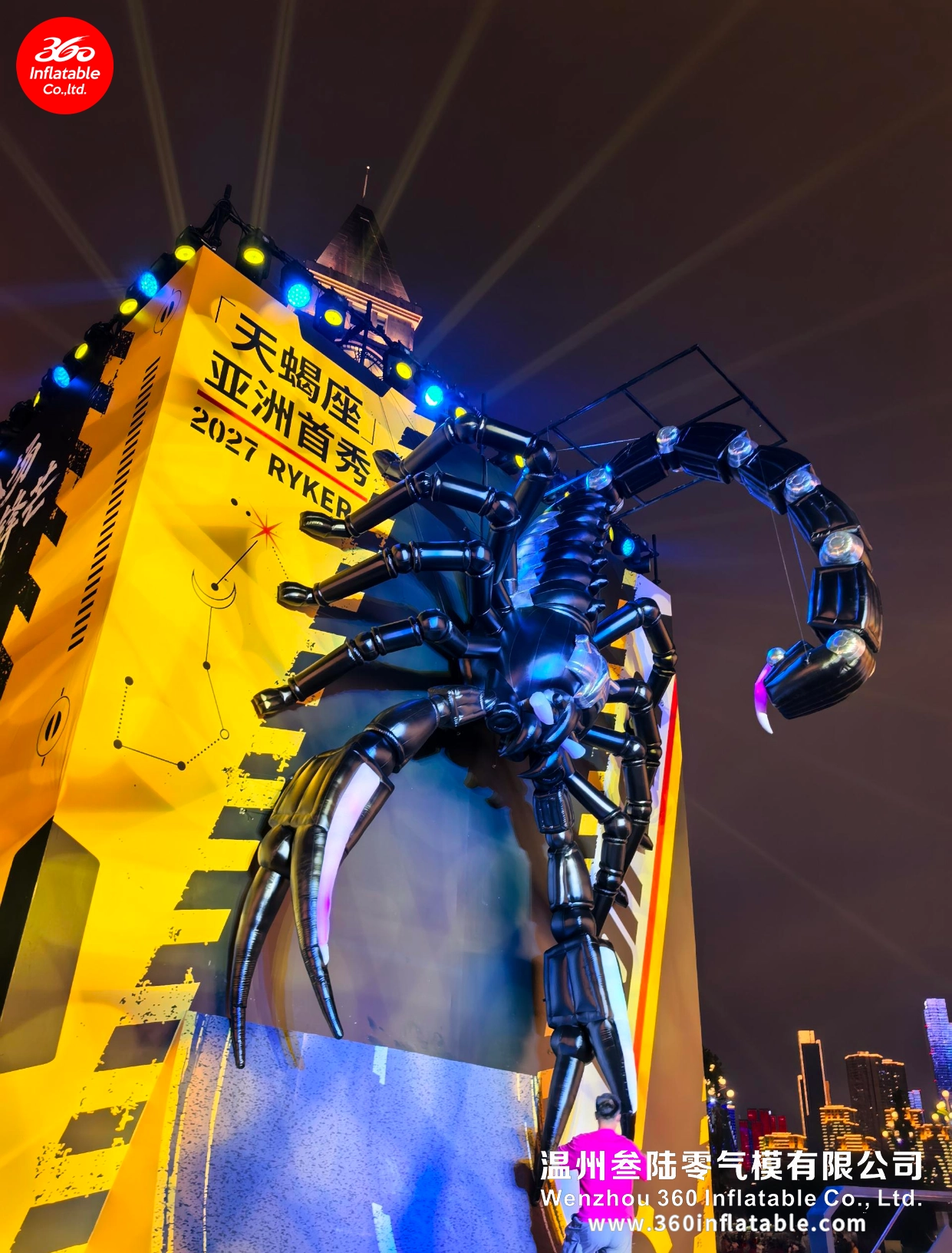 Side view of the Scorpio inflatable showing its raised mechanical tail and climbing posture against the city nightscape.
